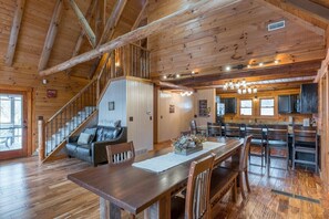 Eine geräumige Holzhütte mit Essbereich, Küche und einer Treppe, die zu einem Schlafboden führt.