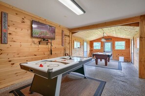 Enjoy entertainment and relaxation in this room, featuring a foosball table and TV for a fun experience.