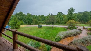 Een houten terras met uitzicht op een verzorgd gazon en bomen.