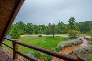 Eine Holzterrasse mit Blick auf einen gepflegten Rasen und Bäume.