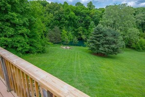 A well-maintained lawn with a wooden deck and dense trees in the background.