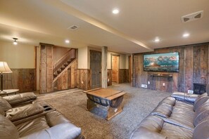 A spacious living room with a large leather sofa, a wooden coffee table, and a mounted TV.
