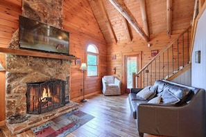 Cozy retreat with a stone fireplace, leather sofa, and TV above the hearth.