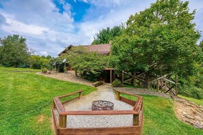 A rustic cabin with a gravel pathway leading to a wooden bench.
