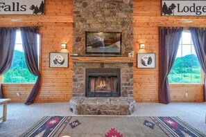 A cozy room with a stone fireplace, a television mounted above it, and framed pictures on the walls.