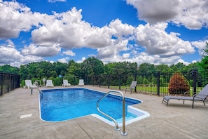 A rectangular swimming pool with a metal ladder, surrounded by a black metal fence. - Falls Lodge | Hocking Hills, 7BR Estate, Pool (Rockbridge)
