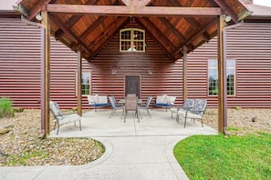 A rustic wooden cabin with a covered patio area featuring a central table and four chairs.