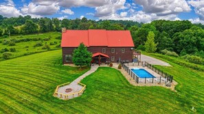 A large house with a red roof, surrounded by a well-maintained lawn and a swimming pool.