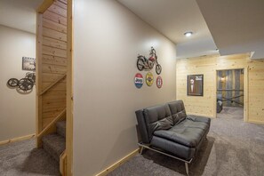 A room with a wooden staircase, a leather sofa, and wall decorations including a motorcycle and various badges.