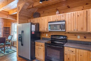 A kitchen with wooden cabinets, a refrigerator, a microwave, and a stove.