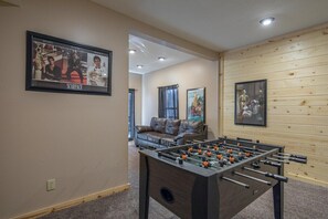 A room with a foosball table, a sofa, and a framed picture on the wall.