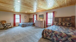 Une chambre avec deux lits, un plafond en bois et une commode.