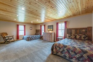 Un dormitorio con dos camas, techo de madera y una cómoda.