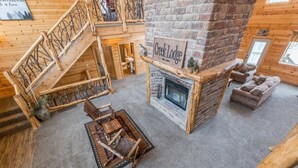 Un intérieur chaleureux et accueillant, avec une cheminée en pierre, un escalier en bois et un coin salon confortable.