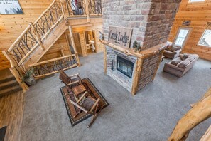 Un acogedor interior de cabaña con chimenea de piedra, escalera de madera y un espacio de descanso confortable.