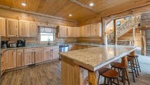 Une cuisine spacieuse dotée de meubles en bois, de plans de travail en granit et d’un îlot central avec des tabourets de bar.