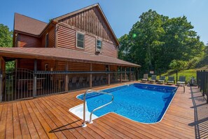 Una cabaña de madera con piscina en una terraza de madera.