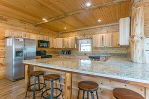 Eine Küche mit Holzwänden, einer Arbeitsplatte aus Granit, einem Edelstahlkühlschrank, einer Mikrowelle und einem Spülbecken.