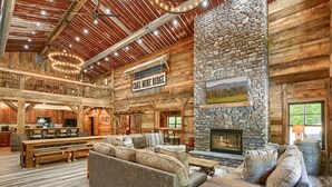 A spacious log cabin interior with a stone fireplace, wooden furniture, and a sign reading "COAL-WINE RIDGE". - Coal Mine | Hocking Hills, 8BR, Pool & Bowling (Logan)