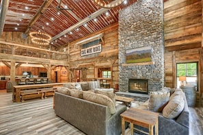 A spacious log cabin interior with a stone fireplace, wooden furniture, and a sign reading "COAL-WINE RIDGE". - Coal Mine | Hocking Hills, 8BR, Pool & Bowling (Logan)