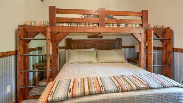 A bunk bed with a wooden frame and a striped pillow. - Coal Mine | Hocking Hills, 8BR, Pool & Bowling (Logan)