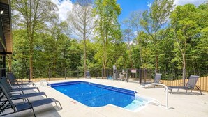 A rectangular swimming pool with a metal ladder, surrounded by lounge chairs and a metal fence. - Coal Mine | Hocking Hills, 8BR, Pool & Bowling (Logan)