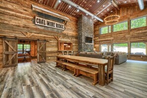 A rustic interior with a large wooden table and benches, a stone fireplace, and a sign reading 'COAL MINE RIDGE.' - Coal Mine | Hocking Hills, 8BR, Pool & Bowling (Logan)