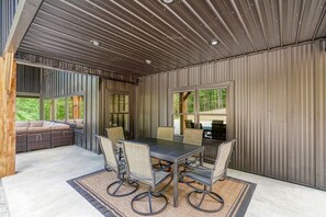 A modern interior with a dining area featuring a table and chairs, a seating area with a sofa, and large windows providing views of the outdoors.