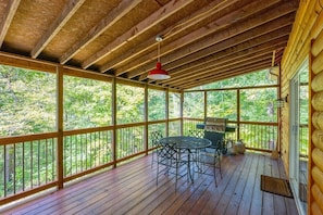 A wooden deck with a table and chairs, surrounded by a wooden railing, overlooking a forested area. - Hideaway Cabin | Hocking Hills, 7 Private Acres (Logan)