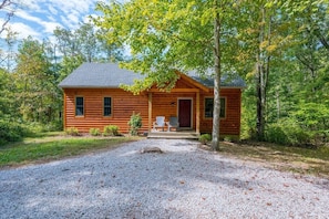 A log cabin with a gravel driveway and a porch with Adirondack chairs. - Hideaway Cabin | Hocking Hills, 7 Private Acres (Logan)