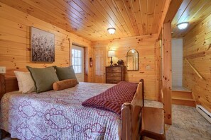 Un dormitori de cabana de fusta amb un llit, un taulell de vestir i un mirall.