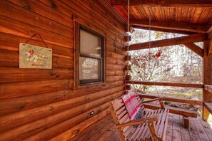 A wooden cabin with a porch, a hanging sign, and a window.