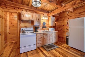 Interior d'una cabana de fusta amb cuina, que disposa d'una cuina, microones i nevera.