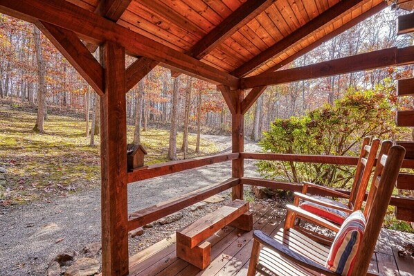 A wooden gazebo with benches and a view of a forest.