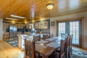 A spacious kitchen with wooden cabinets, a central island, and pendant lighting. - Dragonfly Lodge | Hocking Hills, 5BR, Hot Tub (Logan)