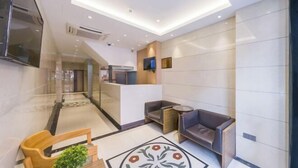 Un vestíbul d'hotel modern amb una recepció, zona de seients i una catifa decorativa.