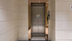 Un ascensor en un passadís amb parets de rajola i un sòl de marbre.