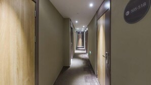 Passadís llarg i estret d'un hotel, amb portes de fusta a un costat i un cartell amb un número de telèfon a l'altre.