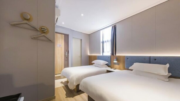 Habitació d'hotel amb dos llits, un armari, un mirall i una finestra.
