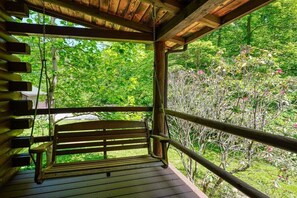 Eine Holzterrasse mit einer Bank, umgeben von üppigem Grün und Bäumen.