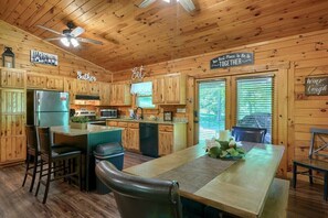 A wooden cabin-style kitchen with a central island, bar stools, and a dining table.