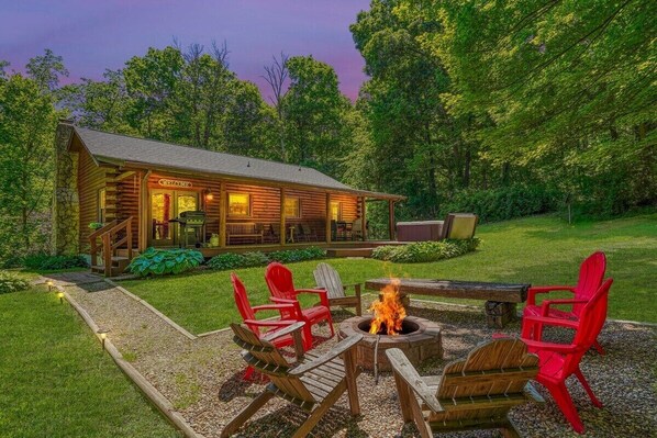 A log cabin with a fire pit and outdoor seating area.