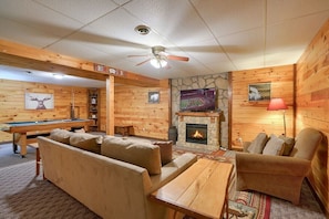 A log cabin interior with a pool table, sofa, and fireplace. - Amazing Starr Cabin | Hocking Hills, Hot Tub, 3BR (Rockbridge)