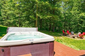 A hot tub on a wooden deck surrounded by a forest.