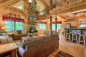 A cozy cabin interior with a fireplace, wooden furniture, and a stone accent wall.