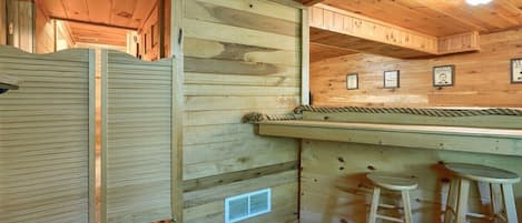 Interior de una cabaña de madera con una barra, taburetes y una puerta.