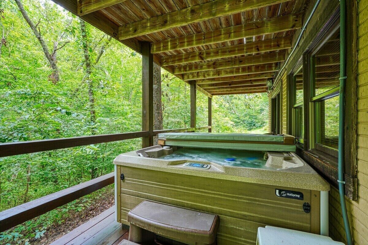 Ein Whirlpool unter einer Holzterrasse mit Blick auf einen Wald.