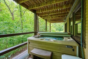 A hot tub under a wooden deck with a view of a forest. - Hickory House | Hocking Hills, 30 Acres, Pets (Logan)