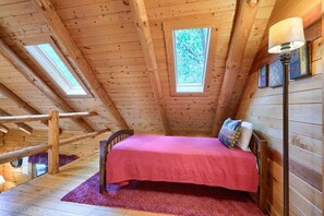 Een houten kamer met een bed, een raam en een lamp.