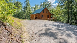 Une cabane en bois avec une allée en gravier, entourée d’arbres.